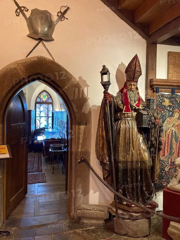 View of left access from historical dining room from reception hall of medieval Trendelburg from the Middle Ages 13th century castle in fairy tale fairy tale castle of Rapunzel today castle hotel Trendelburg, on the right exhibit old historical figure with country of origin Spain of bishop with mitre and lantern, at the top left of the picture old crossed swords and breastplate, Trendelburg, Weserbergland, Hesse, Germany, Europe
