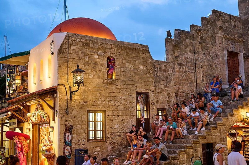 Hippocrates Square, St Paul's Gate, tourists sitting on old walls next to a white building with a red roof, night shot, Rhodes Old Town, Rhodes, Dodecanese, Greek Islands, Greece, Europe