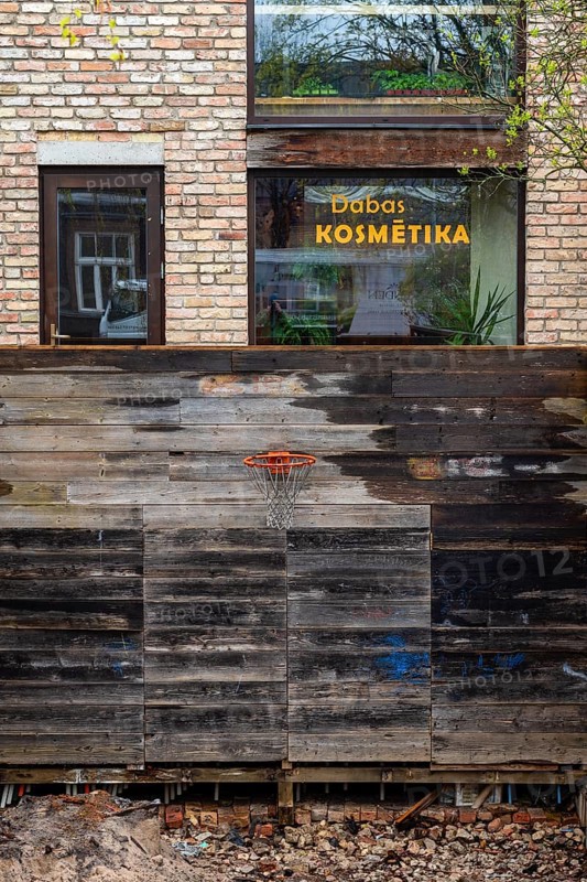 Excavation pit with basketball hoop, behind it a window of a beauty parlour, Riga, Latvia, Europe