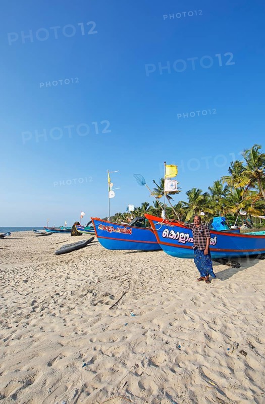 Indian fisherman, 42 years old, and colourful fishing boats at Marari Beach or beach, Mararikulam, Alappuzha district, Kerala, India, Asia