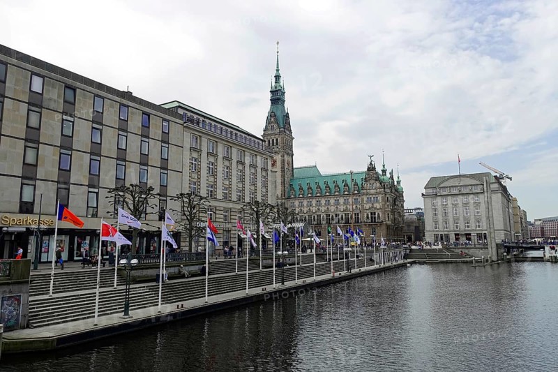 Hamburg City Hall and City Hall Market, Hamburg, Germany, Europe, The City Hall on a river with several flags and buildings under a cloudy sky, Hanseatic City of Hamburg, Europe