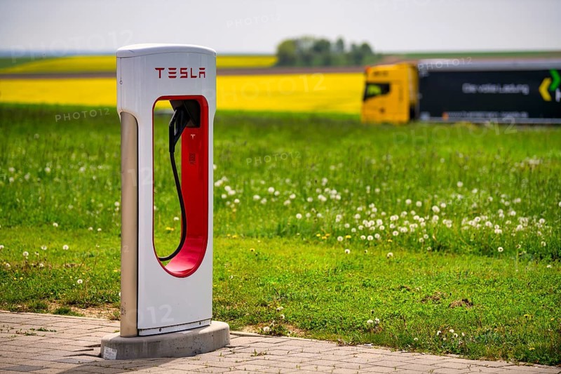 Truck, lorry, lorry drives past Tesla Supercharger in front of rapeseed field, logo, charging station for electric cars, electric charging station, charging station, e-mobility, Ulm, Baden-Wuerttemberg, Germany, Europe