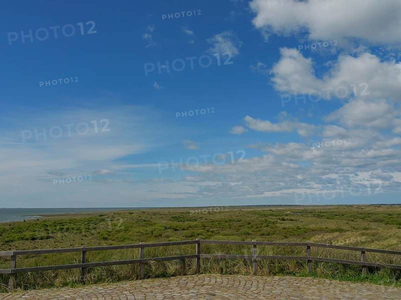 Extensive view of the sea and a green meadow under a partly cloudy sky, dune and beach by the sea with footpaths, grass and lots of sand, nes ameland, the netherlands