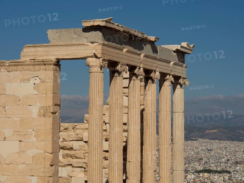 Ancient marble columns with a cityscape and mountains in the background under a clear sky, historical columns and ruins at an ancient site against a blue sky, Athens, Greece, Europe