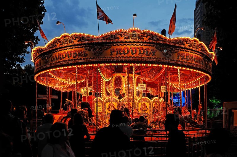 Children's carousel with evening lighting at Queens Walk on the Thames, London, England, Great Britain