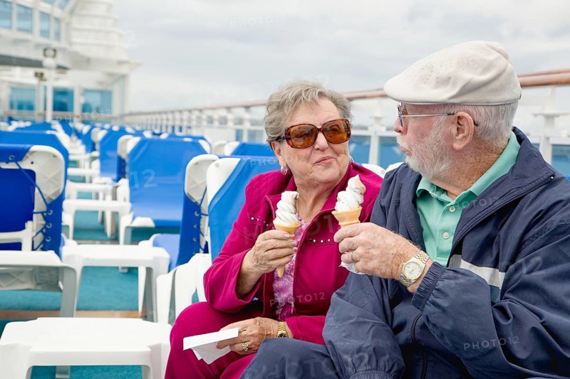 Happy senior adult couple enjoying ice cream on the deck of a luxury passenger cruise ship