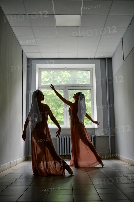 Silhouette of two ballerinas repeat dance steps in the corridor