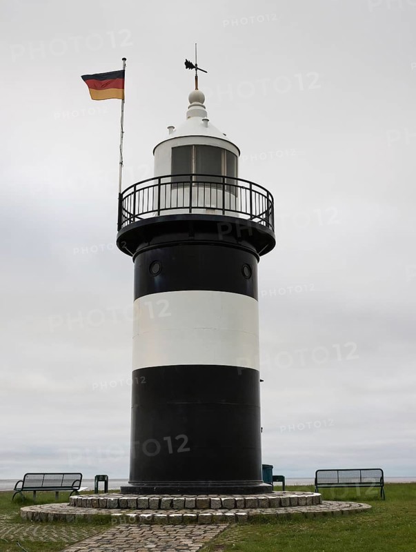 Black and white lighthouse near the North Sea resort of Wremen, called 'Kleiner Preusse', German flag, flag, benches, benches, cloudy sky, coastline at low tide, low tide, close-up, Wurster North Sea coast, Land Wursten, district of Cuxhaven, Lower Saxony, Germany, Europe