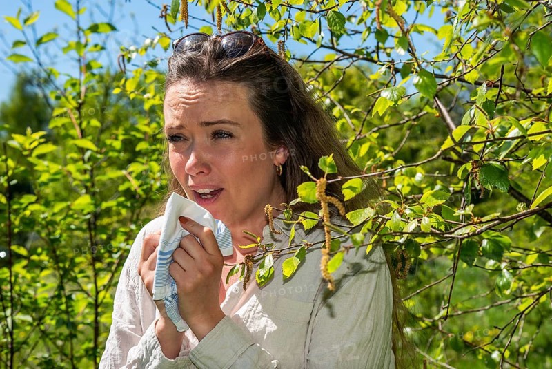 Young Caucasian woman, 35 years old, with allergy stands by flowering birch (Betula) in Ystad, Skane, Sweden, Scandinavia, Europe