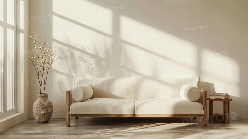 A white couch sits in front of a white wall. Potted feather grass sit on the floor next to the couch. The room is empty and has a minimalist feel. AI generated