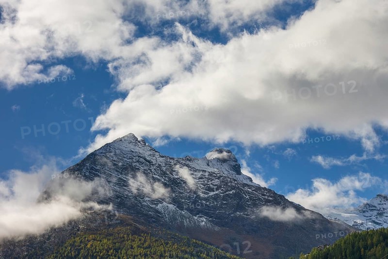 Snow covered mountain peak under a blue sky with scattered clouds, snow on high mountains in the alps, blue sky over mountains, Saas fee, Switzerland, Europe