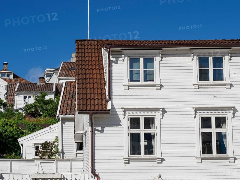 White wooden houses with red tiled roofs against a clear blue sky, white wooden houses with green trees and flowers against a blue sky, Stavanger, Norway, Europe
