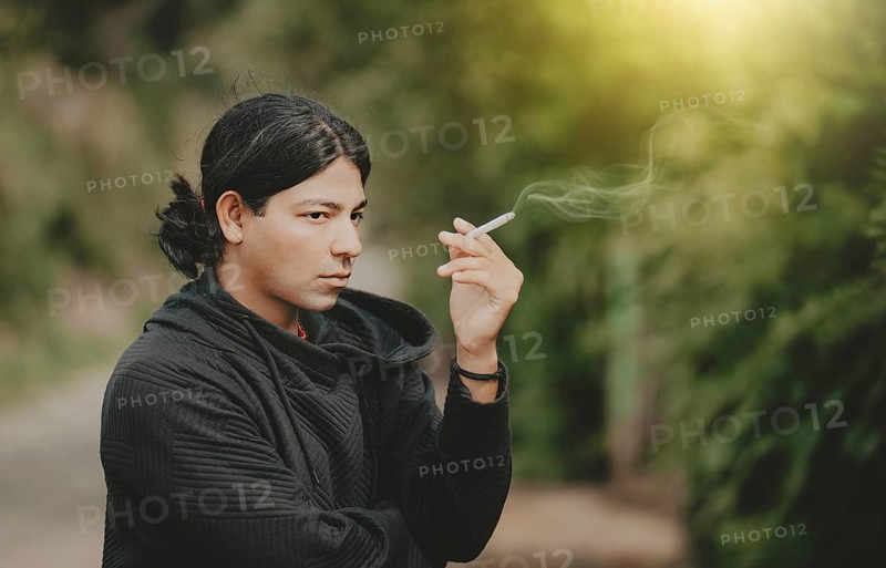 Portrait of handsome guy smoking outdoors. Young man smoking cigarette on the street