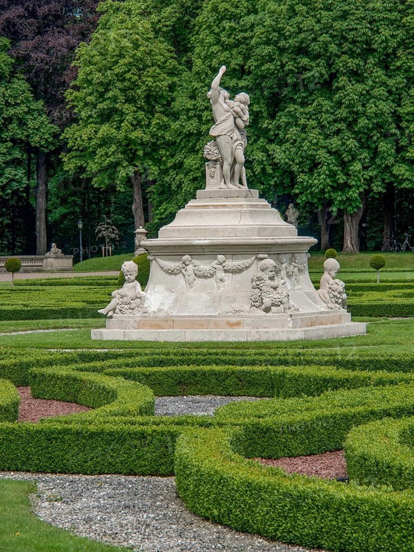 Monumental fountain with several sculptures in a well-kept baroque garden, park with green hedges, small paths and old statues, nordkirchen, germany