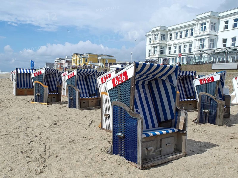 Blue and white beach chairs in a row on the beach in front of white buildings under a sunny sky, blue and white striped beach chairs on the beach, Norderney, Germany, Europe
