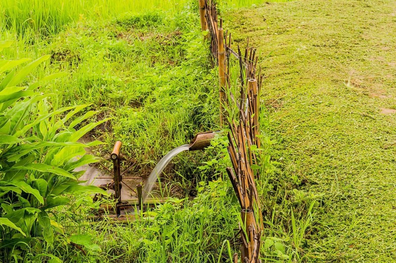 Water flowing from irrigation pipe spinning a small water wheel in canal in Chiang Khan, Thailand, Asia