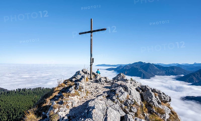 Summit cross at Ettaler Manndl, view over mountain landscape and sea of clouds, high fog in the valley, Ammergau Alps, Bavaria, Germany, Europe
