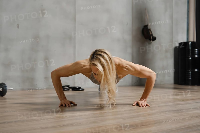 Low angle view of sporty woman doing push ups on the floor in gym