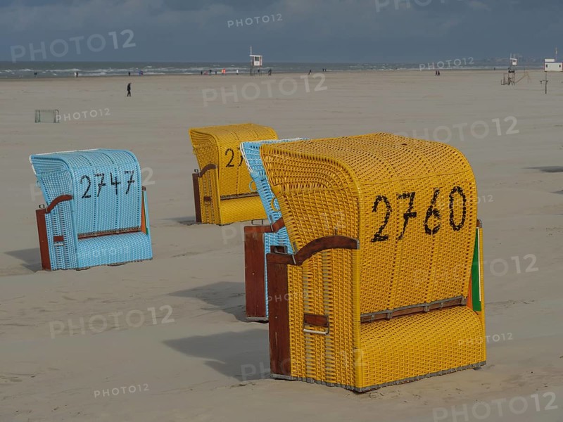 Yellow and blue beach chairs in a sandy landscape on a cloudy day, colourful beach chairs on the beach and in the dunes on a cloudy day, red wooden boat and yellow beach chair, Juist, Germany, Europe