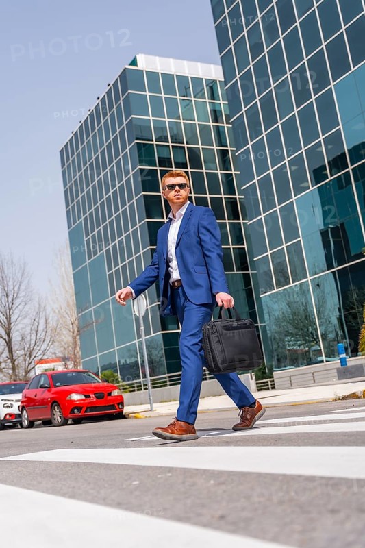 Vertical low angle view of a cool businessman crossing the street in the city