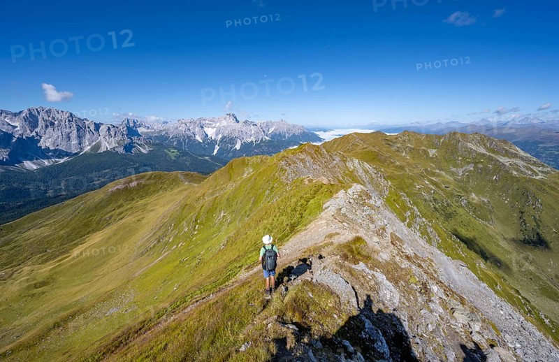Mountaineers on a hiking trail between green mountain meadows on a mountain ridge, mountain panorama, view of rocky mountain peaks of the Sesto Dolomites, Carnic Main Ridge, Carnic High Trail, Carnic Alps, Carinthia, Austria, Europe