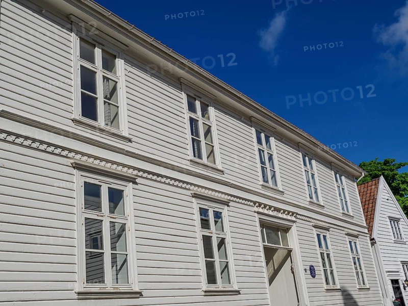 White wooden houses with many windows and red tiled roofs under a blue sky, white wooden houses with green trees and flowers against a blue sky, Stavanger, Norway, Europe