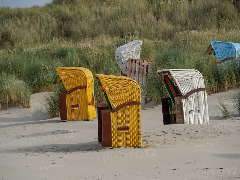 Yellow and white beach chairs on the beach in front of high dunes, a calm atmosphere illustrates, colourful beach chairs on the beach and in the dunes with overcast sky, red wooden boat and yellow beach chair, Juist, Germany, Europe
