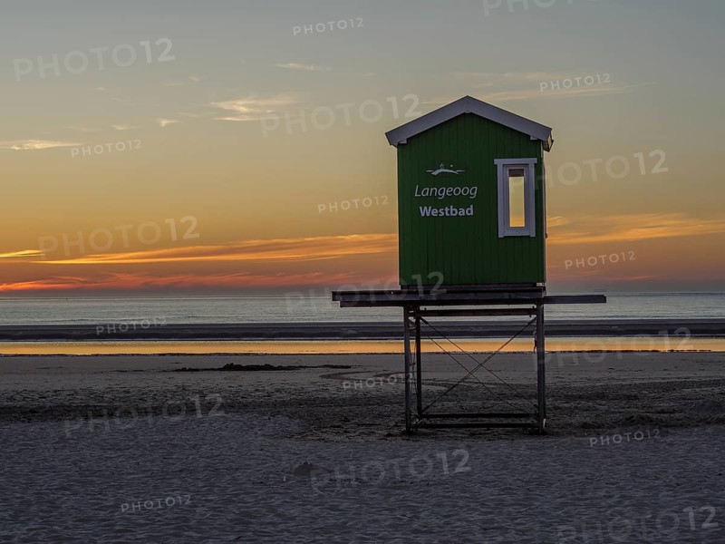 Langeoog Westbad rescue tower on the beach at sunset with a calm sea, beautiful sunset on the beach of an island with beach chairs in the foreground and the calm sea in the background, langeoog, germany