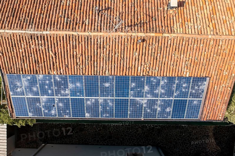 Aerial image of a terracotta tiled roof with a row of damaged solar panels