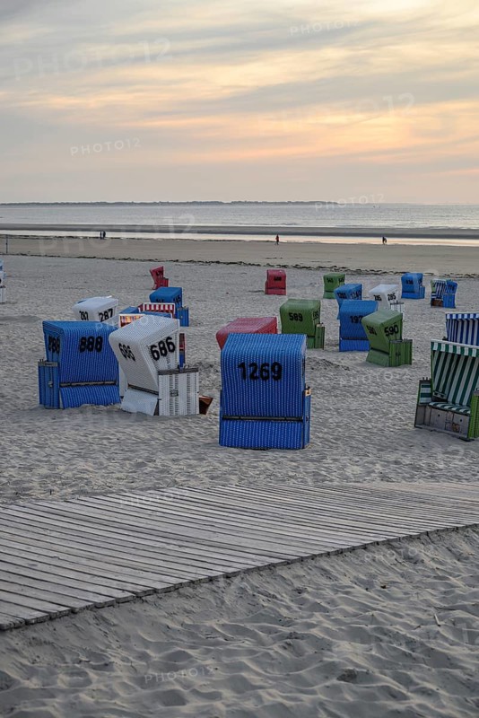Beach chairs and a wooden path on a sandy beach at sunset, many colourful beach chairs on a warm summer evening by the sea, langeoog, germany