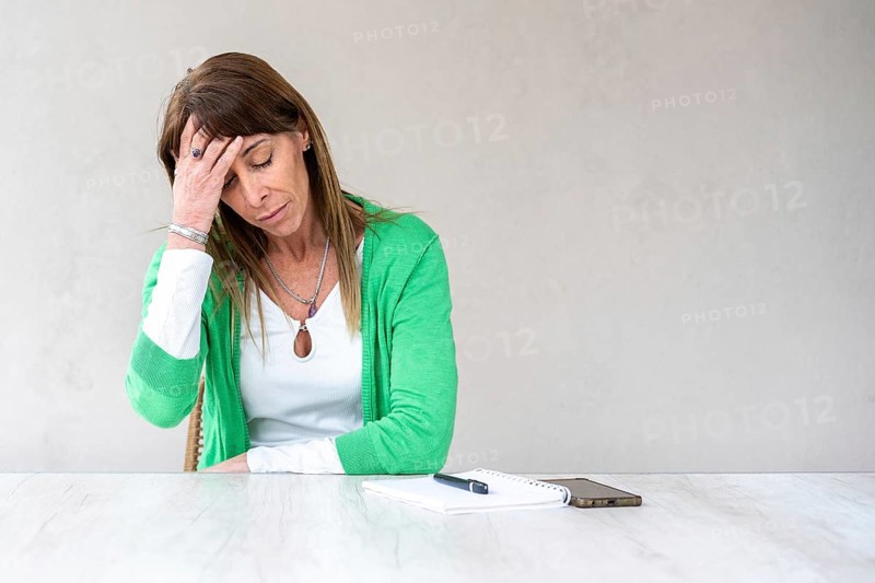A mid-adult woman is holding one hand on her forehead