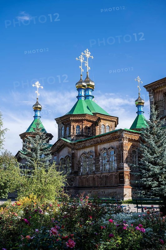 Flowers in front of the Russian Orthodox Church Cathedral of the Holy Trinity, wooden church with green spires, Karakol, Kyrgyzstan, Asia