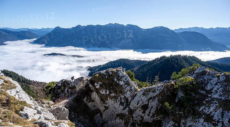 Hiker at Ettaler Manndl, view over mountain landscape and sea of clouds, high fog in the valley, Ammergau Alps, Bavaria, Germany, Europe