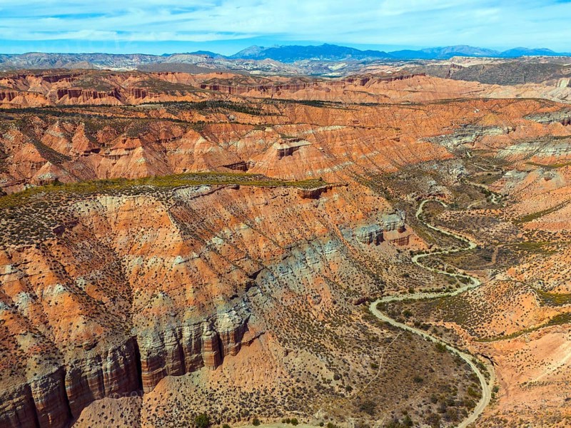 Red rocks and canyons criss-crossed by serpentine roads, embedded in a vast desert landscape, aerial view, Los Coloraos, Grand Canyon of Andalusia, Gorafe desert, Granada, Andalusia, Spain, Europe
