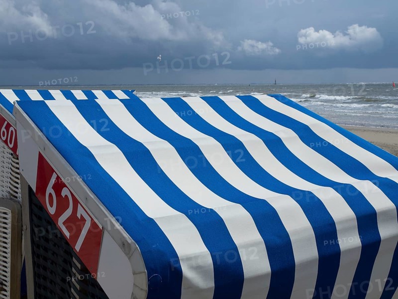 Close-up of blue and white beach chairs on the beach with the sea and a cloudy sky in the background, blue and white striped beach chairs on the beach, Norderney, Germany, Europe
