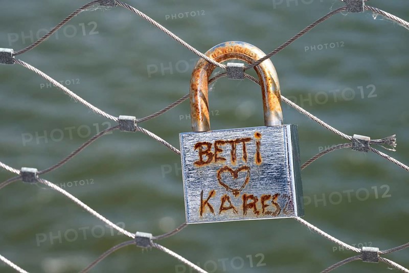 Rusty padlock, love lock, with the inscription Betti Herz Kares on a bridge railing, symbol of old love does not rust, in the background the water of the Danube, Deggendorf, Bavaria, Germany, Europe