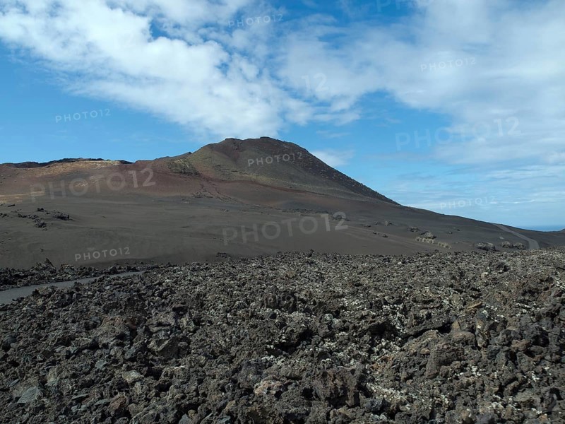 Vast desert landscape with volcano in the background and blue sky, barren landscape of lava mountains, lanzarote, spain