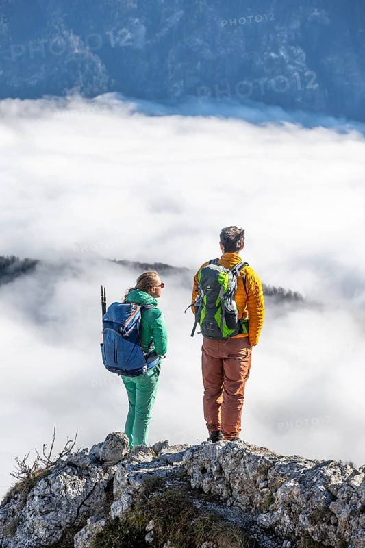 Two hikers at Ettaler Manndl, view over mountain landscape and sea of clouds, high fog in the valley, Ammergau Alps, Bavaria, Germany, Europe