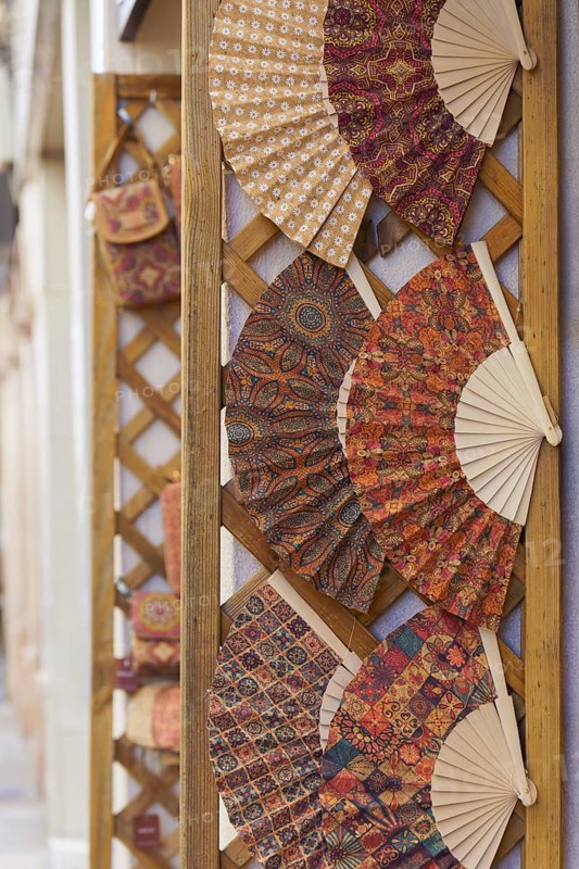 Colorful handmade fans typical of spain displayed in a store in the street