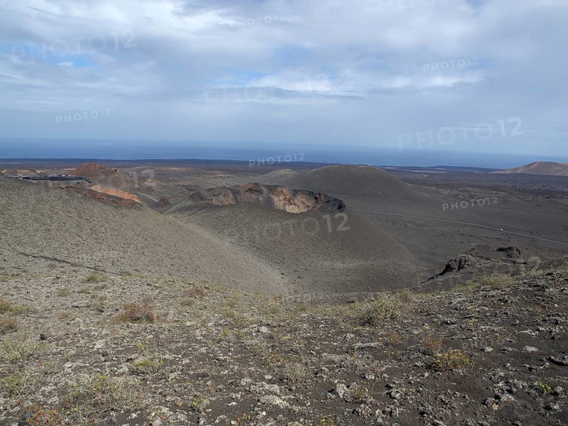 Vast desert landscape with views of the ocean and sky with clouds, barren landscape of lava mountains, lanzarote, spain