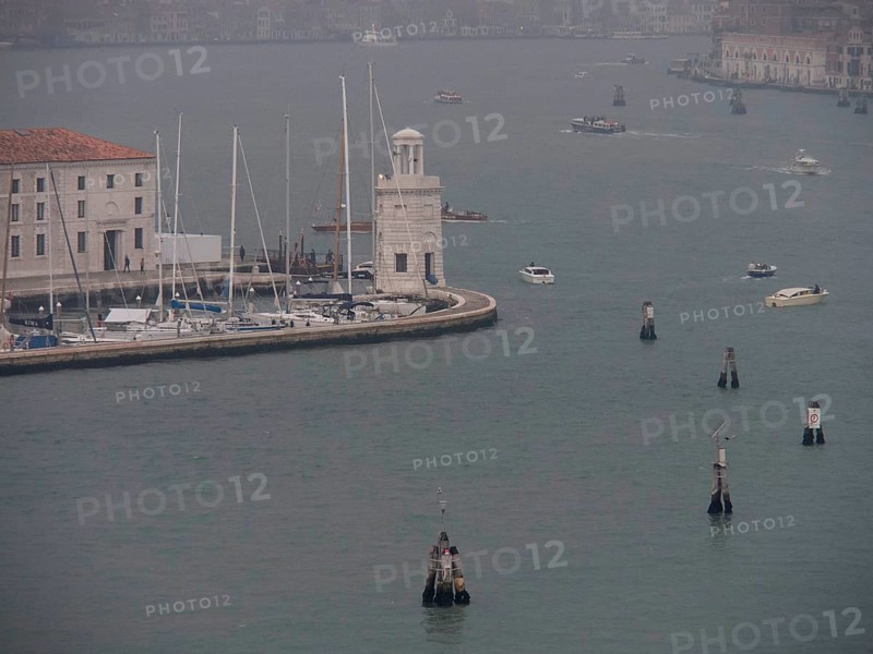 Venetian harbour with boats and yachts and a harbour wall surrounded by a foggy atmosphere, church towers and historic buildings on a large canal, view of Venice from the water, Venice, Italy, Europe