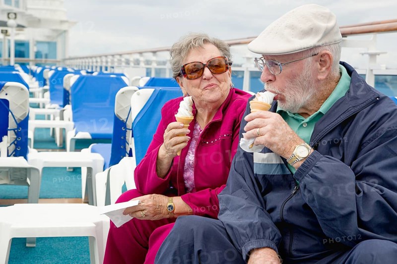 Happy senior adult couple enjoying ice cream on the deck of a luxury passenger cruise ship