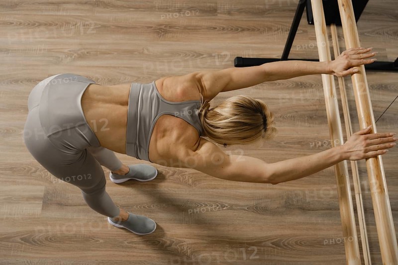 Top view of woman stretching back and arms in gym using handrails