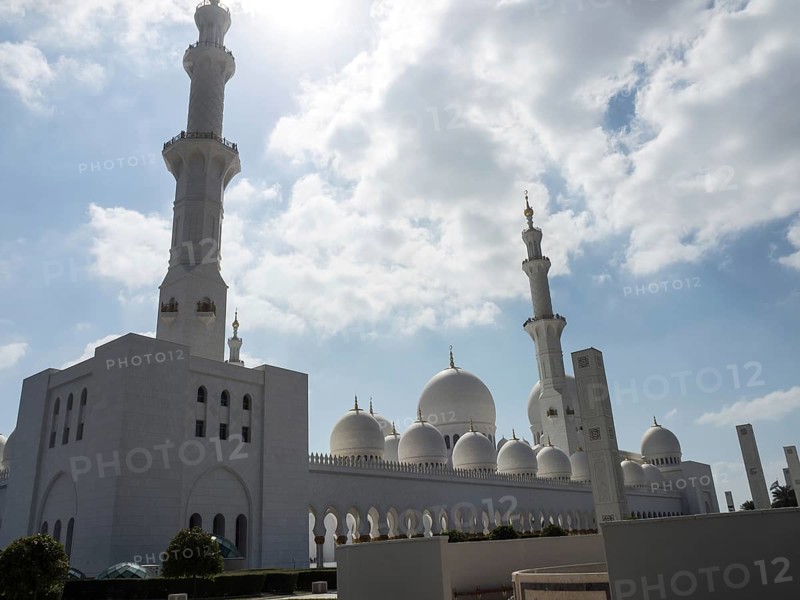 The grandiose mosque lends the sublime architecture a special beauty under the radiant sky, large mosque with white domes and large minarets, abu dhabi, arab emirates