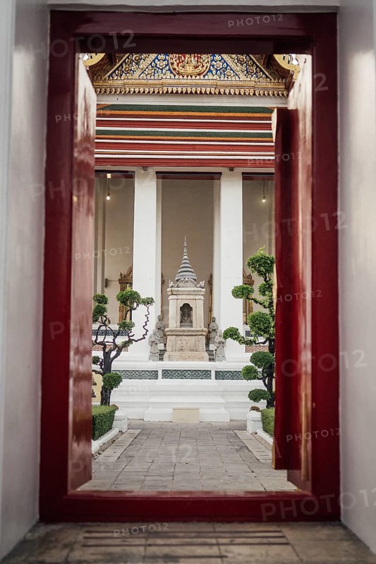 Entrance door to the temple with a view of the shrine, colourfully decorated details. Taken at sunset in Bangkok, Thailand, Asia