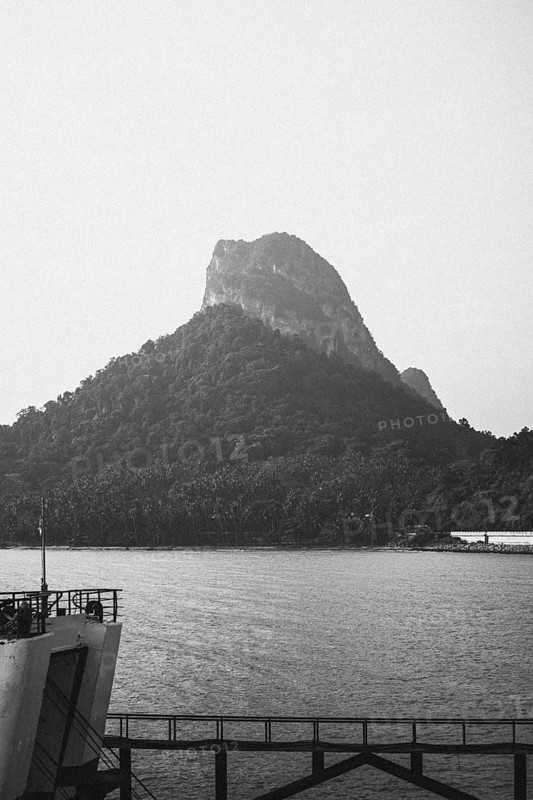 The quiet majesty of a rocky mountain formation shrouded in mist and in black and white. Surat Thani, Thailand, Asia