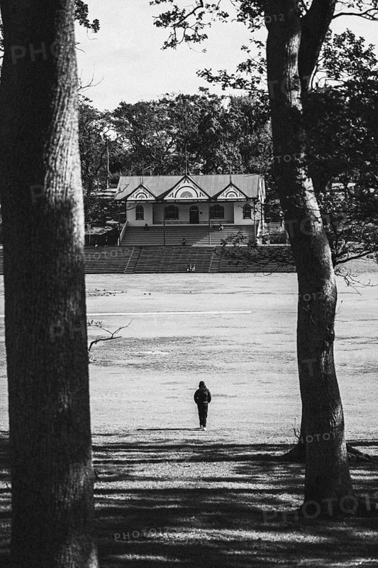 A person walks towards a building through the park. Taken in black and white in Auckland, New Zealand, Oceania