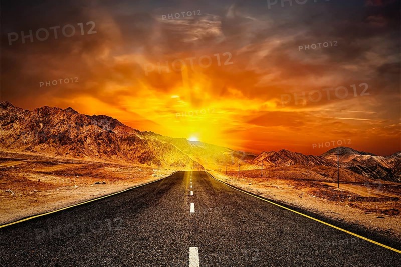 Travel forward concept background, road in Himalayas with mountains and dramatic clouds on sunset. Ladakh, Jammu and Kashmir, India, Asia