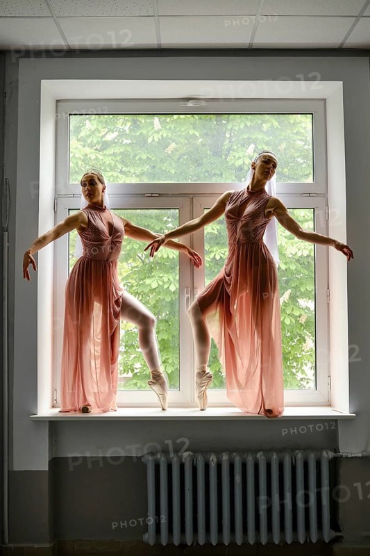Silhouette of two ballerinas perform dance moves while standing on a windowsill in a hallway