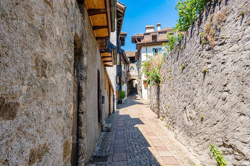 Narrow alley with cobblestone alleyway and old buildings, surrounded by stone walls and flowers, creates a historic and rustic atmosphere, Saint Saphorin, Vaud, Switzerland, Europe